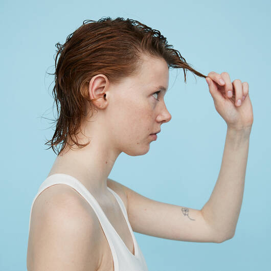 kvinde der står med hårpleje i sit hår