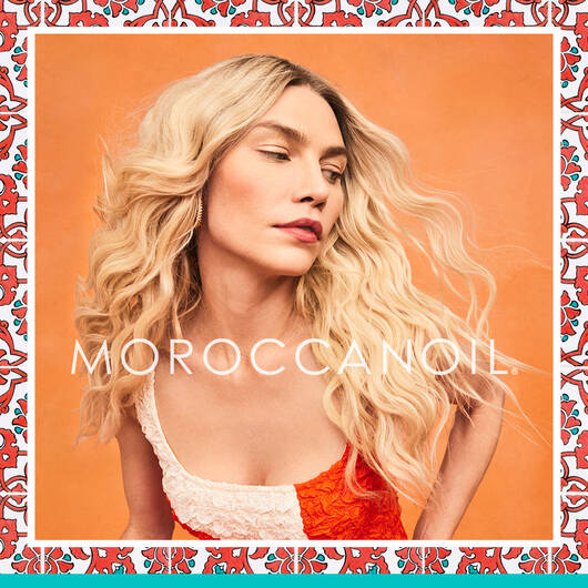 kvinde der står med flot lyst hår efter at have brugt moroccanoil produkter